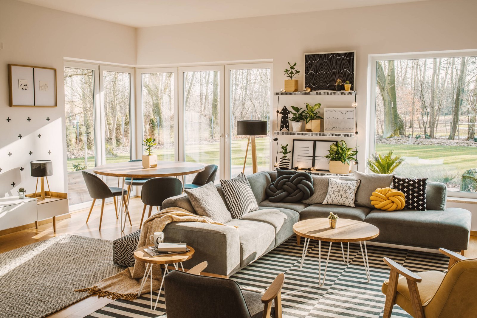 Wooden, round dining table in the corner of an open space living Wooden, round dining table in the corner of an open space living room interior with nordic furniture and decor