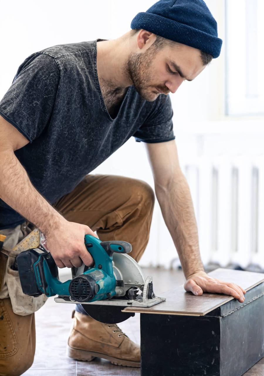 Building contractor worker using hand held worm drive circular saw to cut boards on a new home constructiion project.
